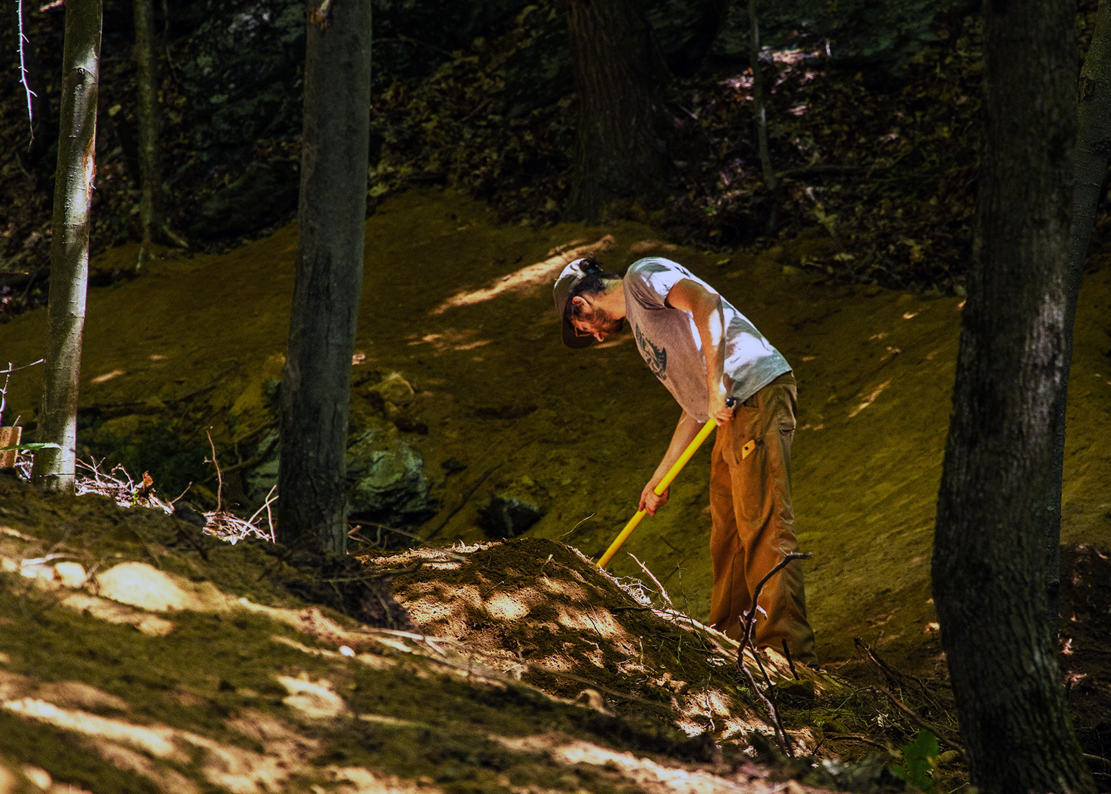 A person raking a trail through the shaded woods